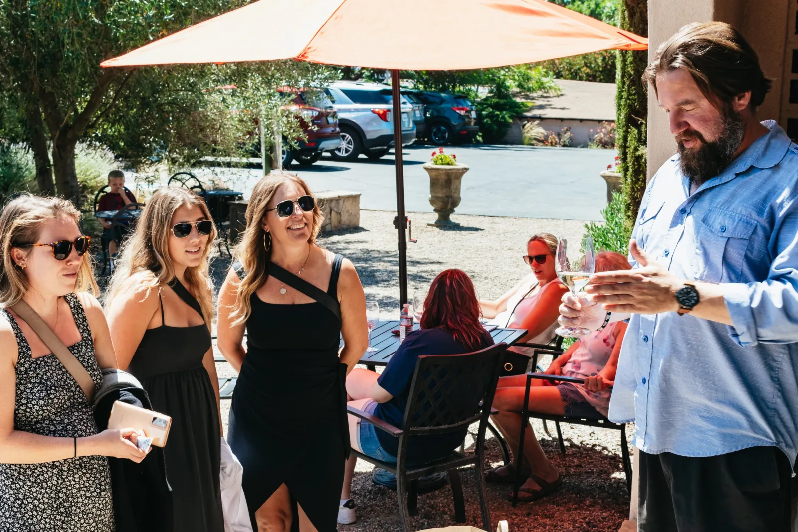 Tour group tasting wine on a shaded winery patio