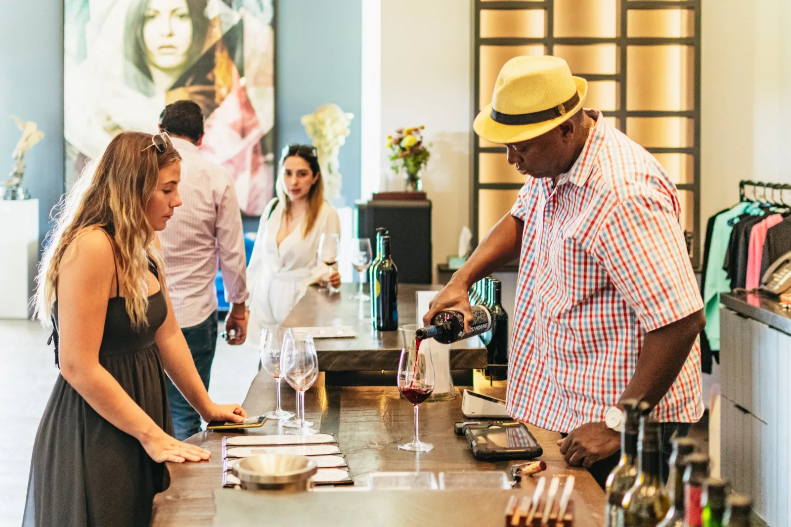 Guest having a glass of red wine poured at a winery tasting counter