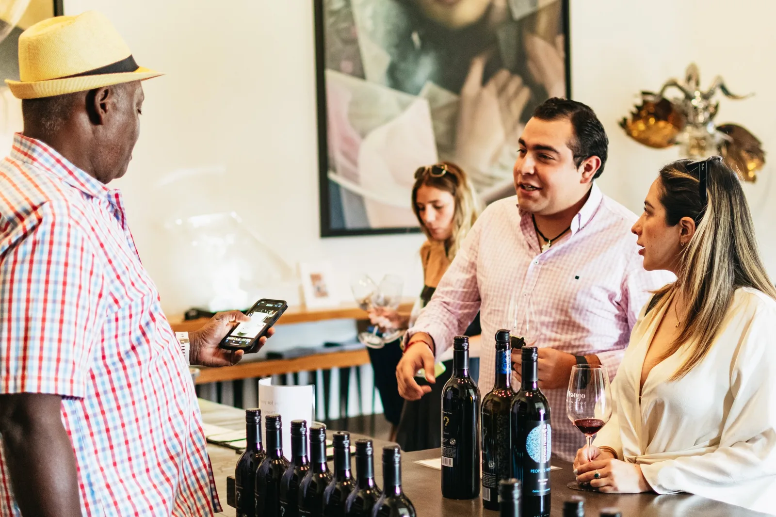 Guests tasting wine at a winery counter lined with bottles