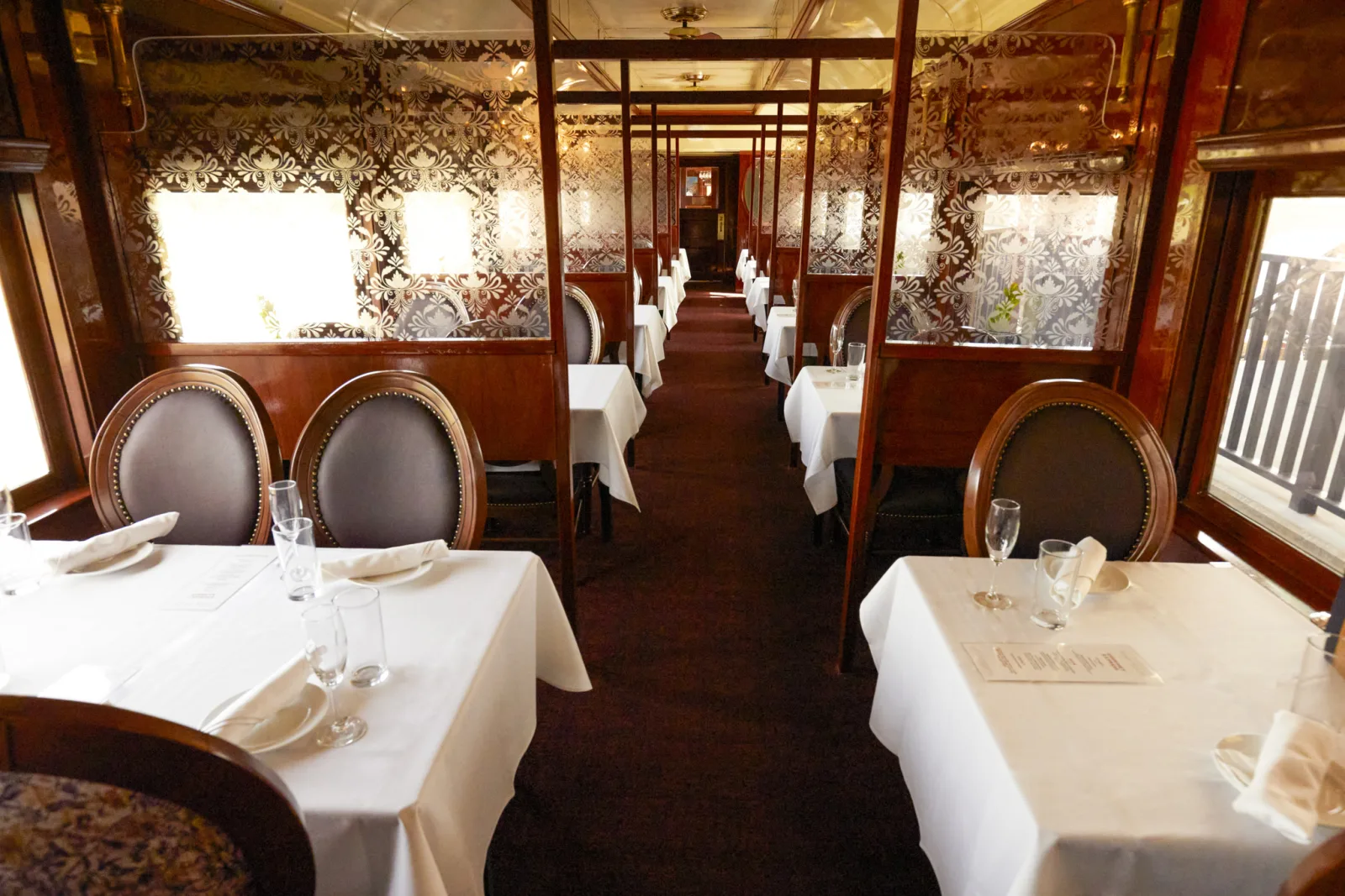 Elegant dining car interior on the Napa Valley Wine Train set with white linen tables