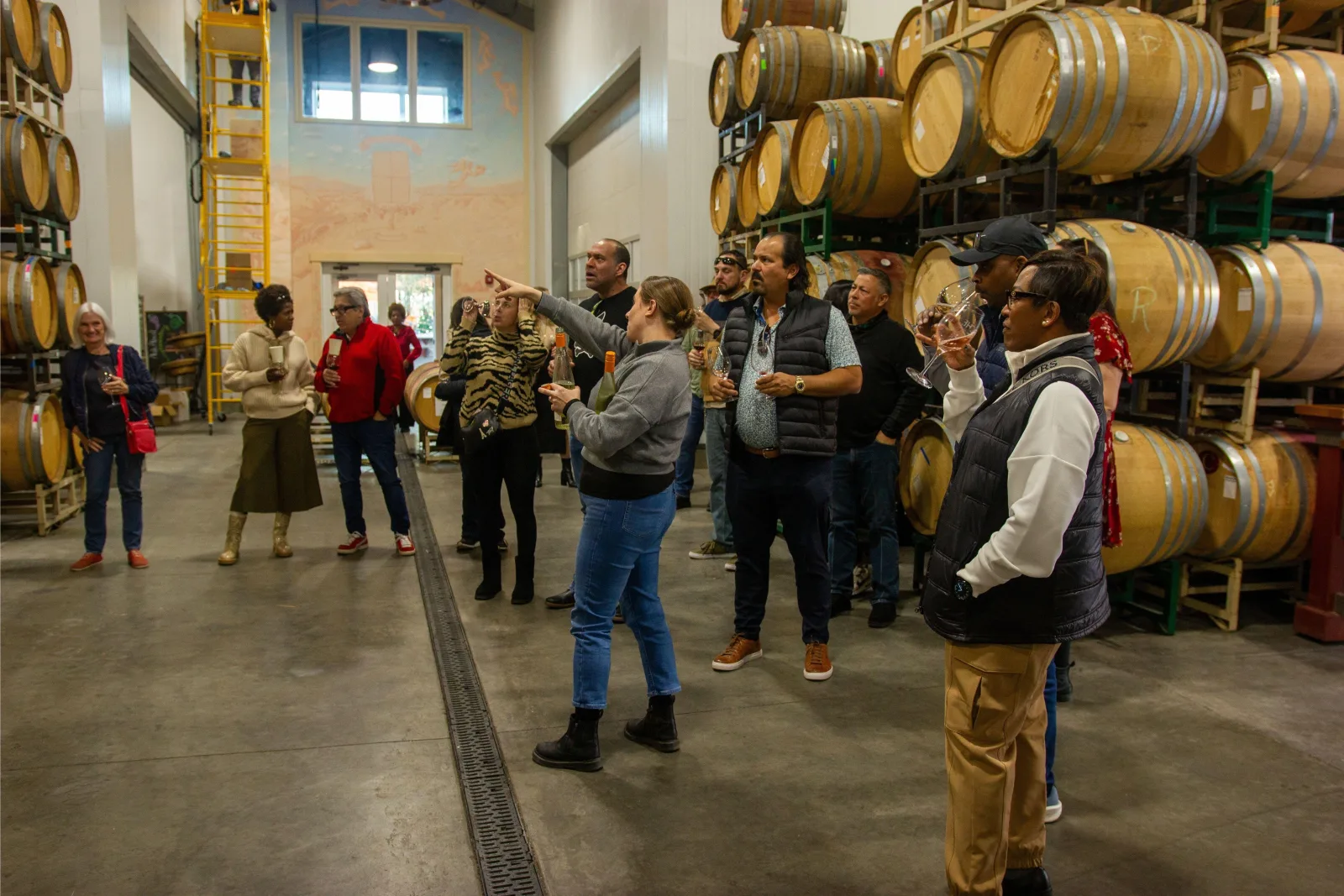 Tour group tasting wine among barrels inside a Napa Valley winery