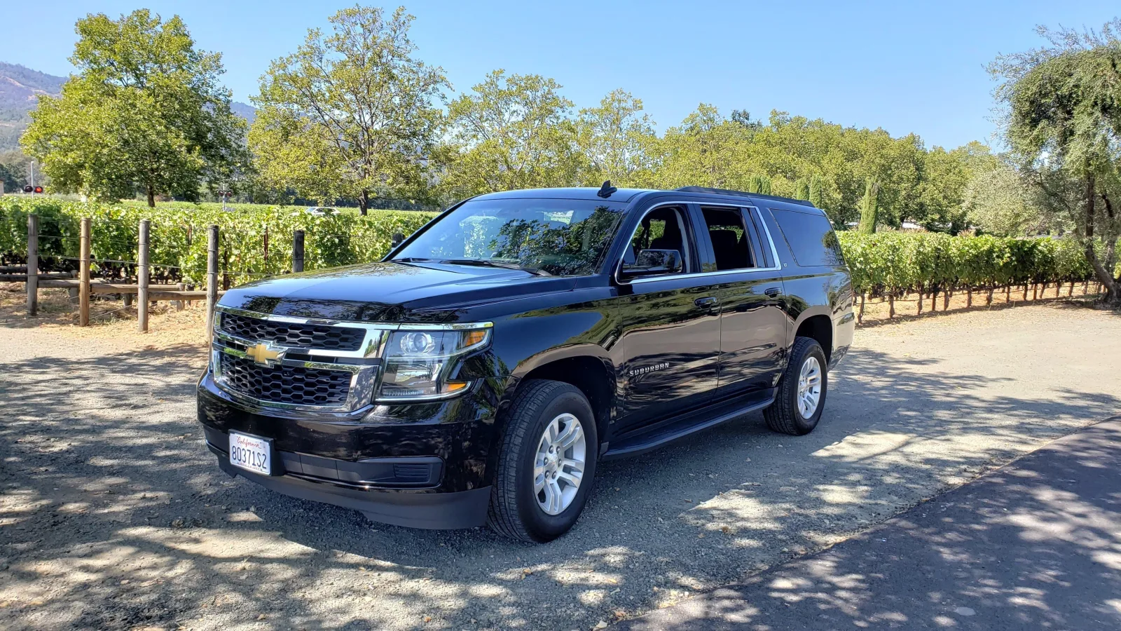 Black chauffeured SUV parked beside a Napa Valley vineyard